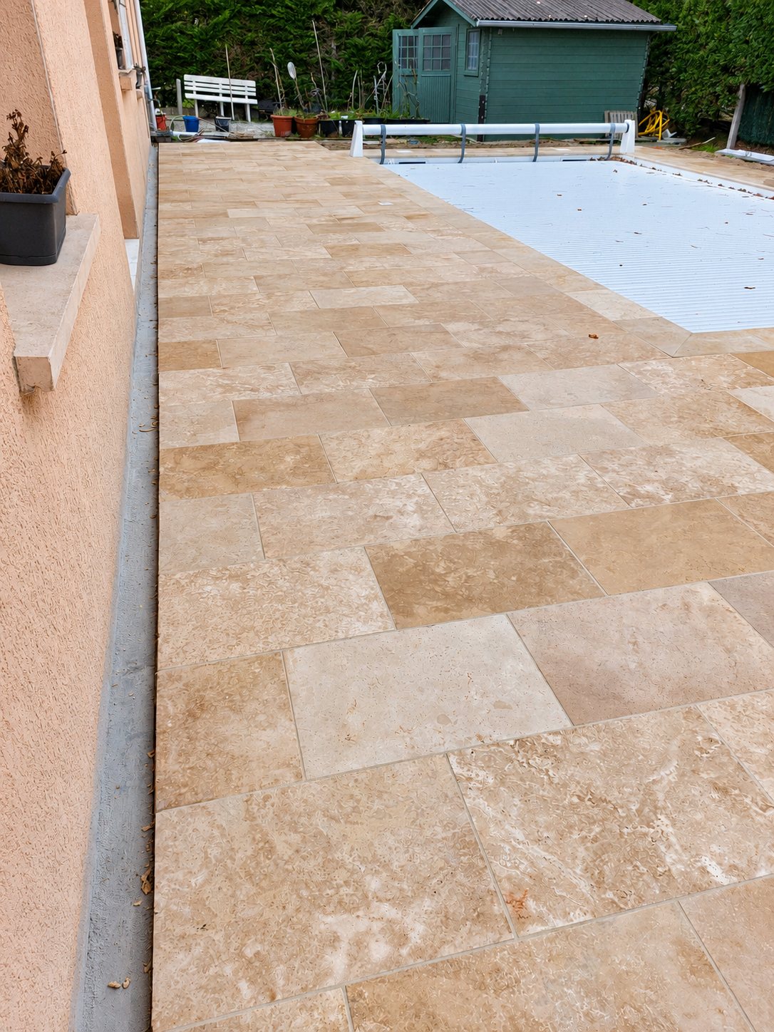 Terrasse en dalles de travertin beige autour d'une piscine couverte